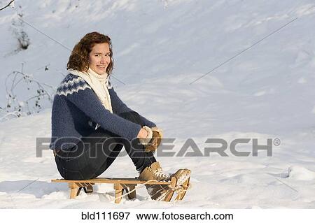 Caucasian woman sitting on sled in snow View Large Photo Image Stock Photo - Caucasian woman sitting on sled in snow. Fotosearch