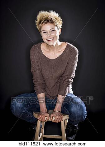 Stock Image - Caucasian woman smiling on bench. Fotosearch
