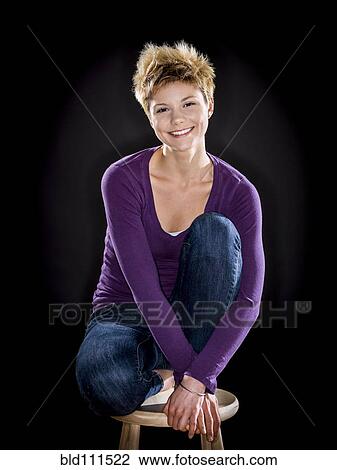 Stock Image - Caucasian woman smiling on bench. Fotosearch