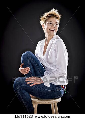 Stock Image - Caucasian woman smiling on bench. Fotosearch