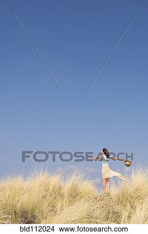 Picture - Caucasian woman standing in tall grass. Fotosearch