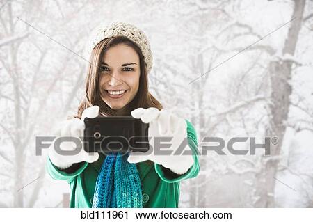 Stock Image - Caucasian woman taking pictures in snow. Fotosearch