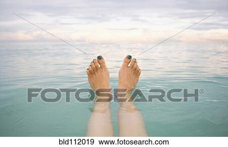 Stock Photo - Caucasian woman's feet floating in tropical water. Fotosearch