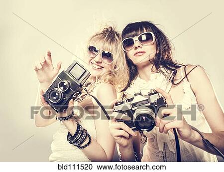 Stock Image - Caucasian women posing with cameras. Fotosearch