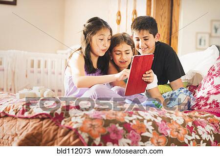 Stock Image - Children using digital tablet together. Fotosearch