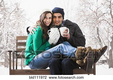 Stock Image - Couple having coffee together in snow. Fotosearch