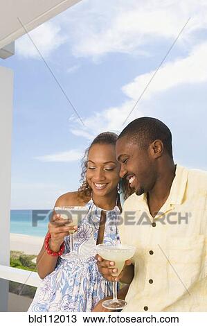 Couple having drinks on balcony View Large Photo Image Stock Image - Couple having drinks on balcony. Fotosearch