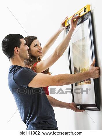 Couple measuring picture frame on wall View Large Photo Image Stock Image - Couple measuring picture frame on wall. Fotosearch