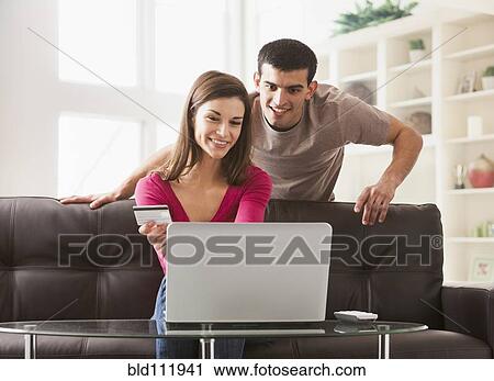 Stock Image - Couple shopping online on sofa. Fotosearch