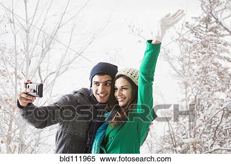 Stock Photography - Couple taking pictures together in snow. Fotosearch