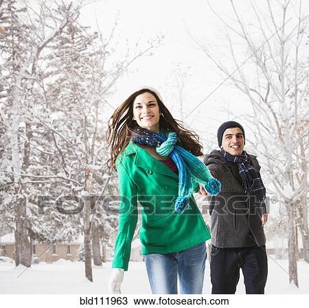 Stock Image - Couple walking together in snow. Fotosearch