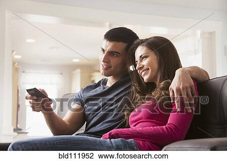 Stock Image - Couple watching television on sofa. Fotosearch