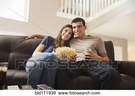 Stock Photo - Couple watching television on sofa. Fotosearch