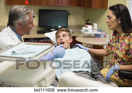 Stock Photo - Dentist and nurse examining patient's mouth. Fotosearch