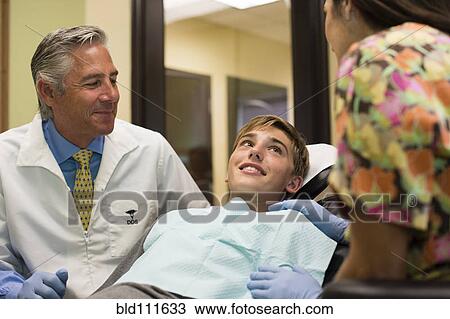 Stock Image - Dentist and nurse talking to patient. Fotosearch