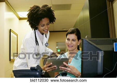 Stock Image - Doctor and nurse using digital tablet. Fotosearch