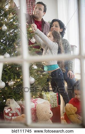 Stock Photography - Family decorating Christmas tree together. Fotosearch