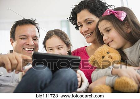 Stock Image - Family using digital tablet together on sofa. Fotosearch