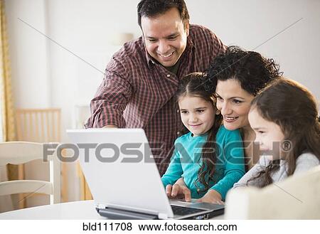 Stock Photo - Family using laptop together at table. Fotosearch