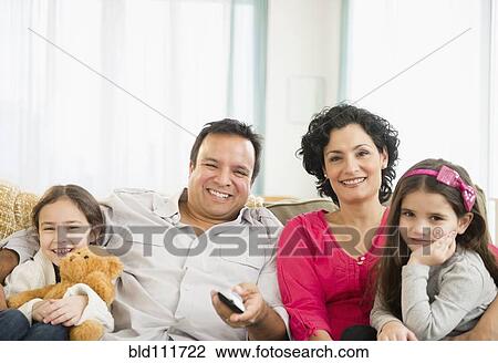 Stock Image - Family watching television together on sofa. Fotosearch