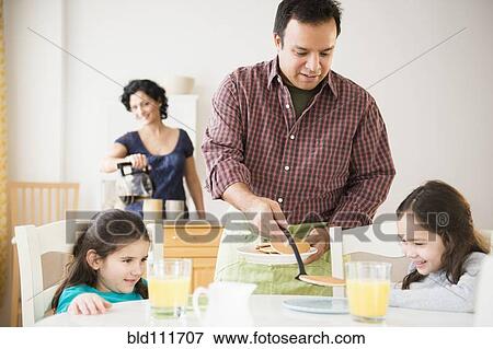 Father serving daughters breakfast at table View Large Photo Image Stock Photo - Father serving daughters breakfast at table. Fotosearch