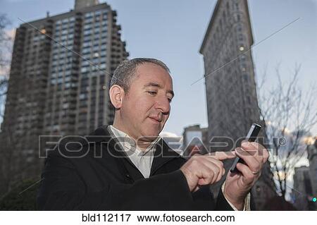Hispanic businessman using cell phone in city View Large Photo Image Stock Photo - Hispanic businessman using cell phone in city. Fotosearch