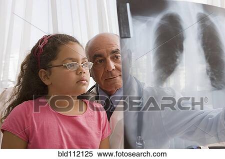 Stock Photography - Hispanic doctor showing chest x-rays to patient. Fotosearch