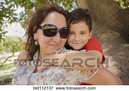 Stock Photo - Hispanic mother carrying son piggyback. Fotosearch