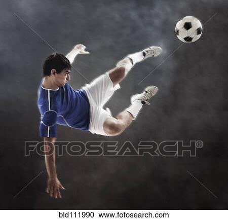 Stock Image - Hispanic soccer player kicking ball in mid air. Fotosearch
