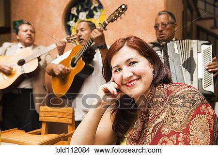 Picture - Hispanic woman in restaurant with Mariachi band. Fotosearch