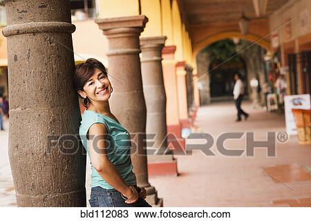 Stock Image - Hispanic woman leaning on column. Fotosearch