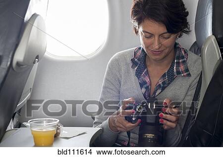 Picture - Hispanic woman using camera in airplane. Fotosearch