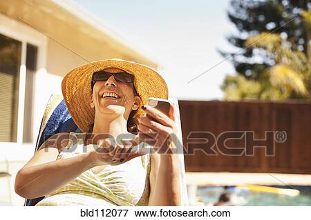 Hispanic woman using cell phone by pool View Large Photo Image Stock Photo - Hispanic woman using cell phone by pool. Fotosearch