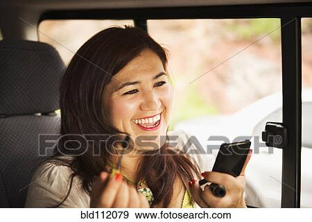 Stock Photo - Hispanic woman using cell phone in car. Fotosearch