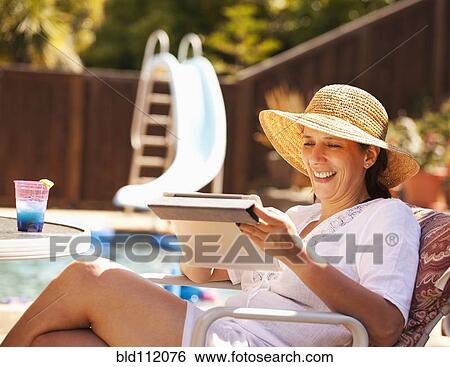 Hispanic woman using digital tablet by pool View Large Photo Image Stock Photograph - Hispanic woman using digital tablet by pool. Fotosearch
