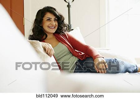 Stock Photo - Middle Eastern woman relaxing on sofa. Fotosearch