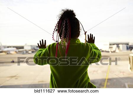 Stock Photo - Mixed race girl looking out airport window. Fotosearch