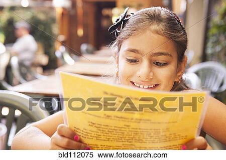 Stock Photography - Mixed race girl reading menu in restaurant. Fotosearch