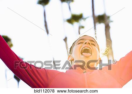 Stock Photo - Mixed race girl sticking tongue out outdoors. Fotosearch