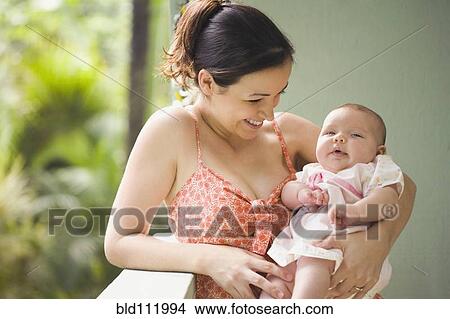 Picture - Mixed race mother smiling at baby. Fotosearch