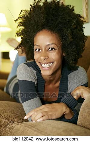 Stock Image - Mixed race woman relaxing on sofa. Fotosearch