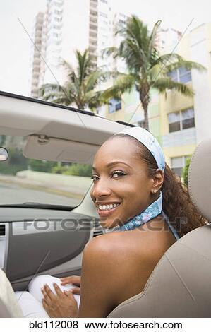 Stock Photo - Mixed race woman riding in convertible. Fotosearch