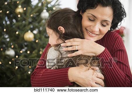 Mother and daughter hugging by Christmas tree View Large Photo Image Stock Image - Mother and daughter hugging by Christmas tree. Fotosearch