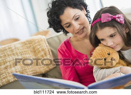 Picture - Mother and daughter reading together on sofa. Fotosearch