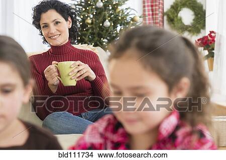 Mother watching daughters in living room View Large Photo Image Picture - Mother watching daughters in living room. Fotosearch