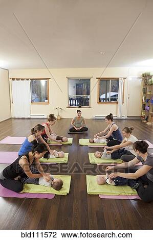 Stock Image - Mothers and babies taking yoga class. Fotosearch