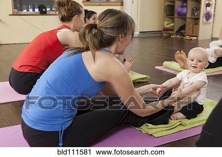 Stock Image - Mothers and babies taking yoga class. Fotosearch