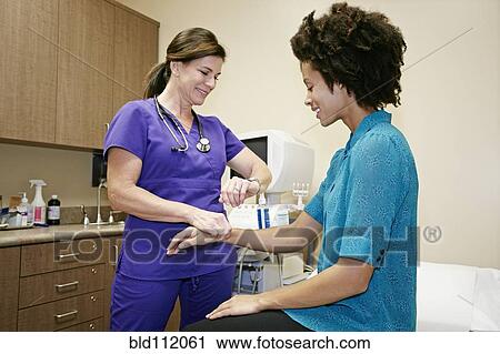 Stock Image - Nurse checking patient's pulse in office. Fotosearch