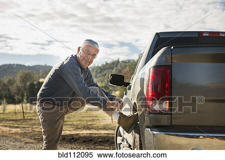 Older Caucasian man tying his shoe on truck wheel View Large Photo Image Stock Photography - Older Caucasian man tying his shoe on truck wheel. Fotosearch
