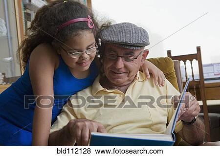 Stock Photo - Older Hispanic man reading to granddaughter. Fotosearch